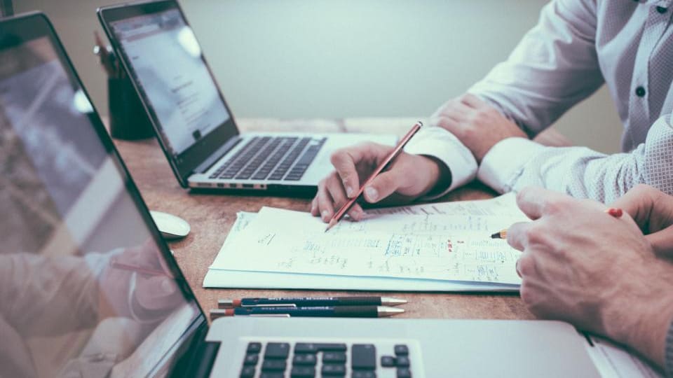 Personas revisando documentos y anotando sobre una mesa de trabajo