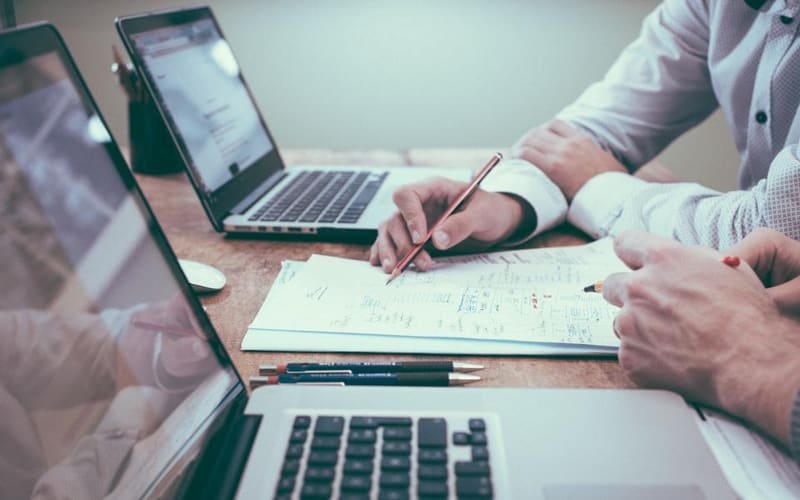 Personas revisando documentos y anotando sobre una mesa de trabajo